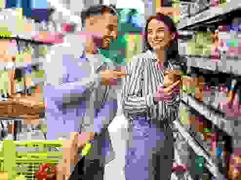 A young couple smiling grocery shopping